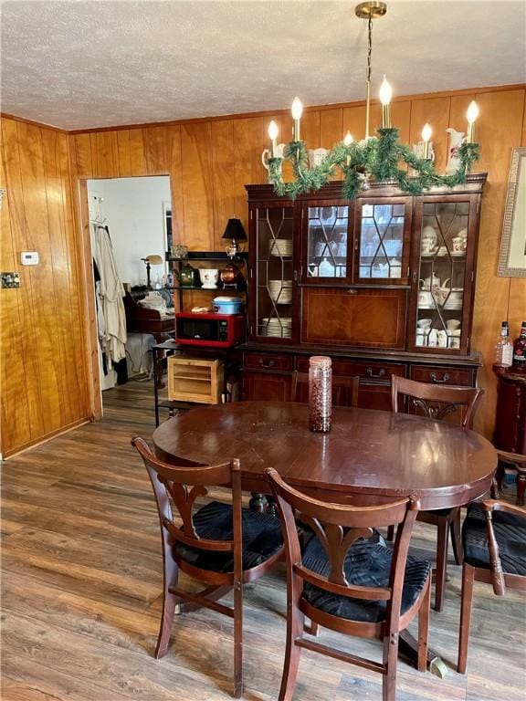 dining room featuring hardwood / wood-style flooring, wooden walls, and a textured ceiling