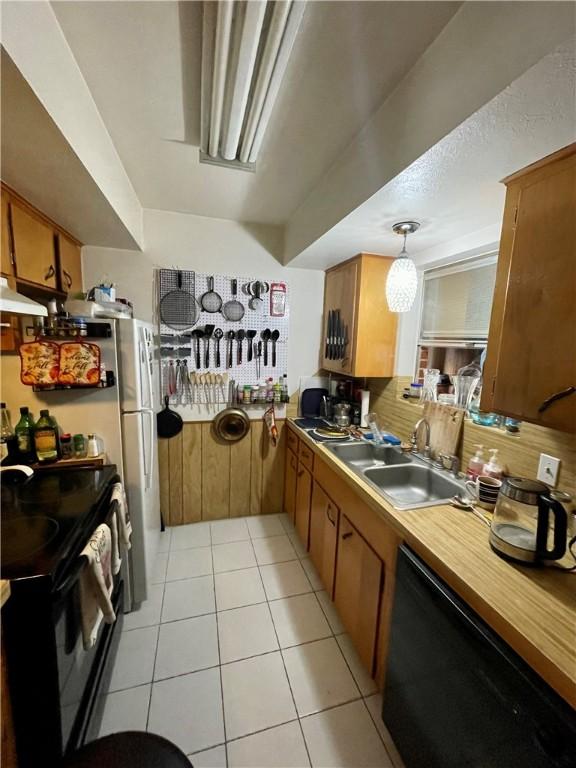 kitchen with pendant lighting, sink, light tile patterned floors, black appliances, and decorative backsplash