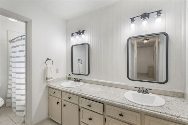 bathroom with a sink, toilet, double vanity, and tile patterned floors