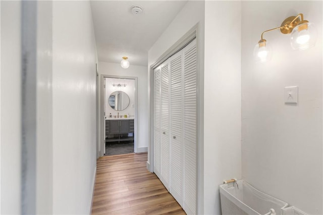 corridor featuring wood finished floors and a sink