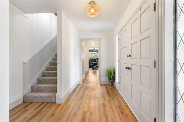 entrance foyer with baseboards, stairs, and light wood finished floors