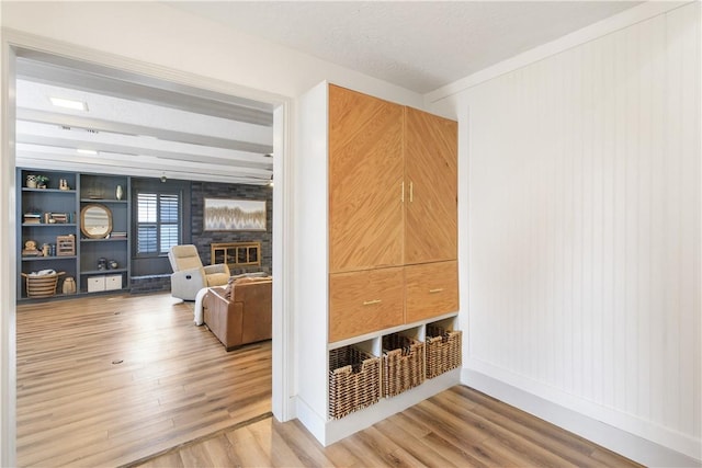 unfurnished living room featuring a glass covered fireplace, a textured ceiling, baseboards, and wood finished floors