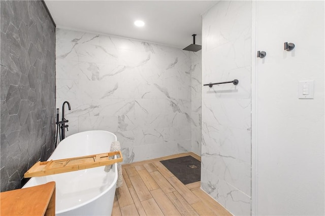 full bath with wood finished floors, a marble finish shower, recessed lighting, a freestanding bath, and tile walls