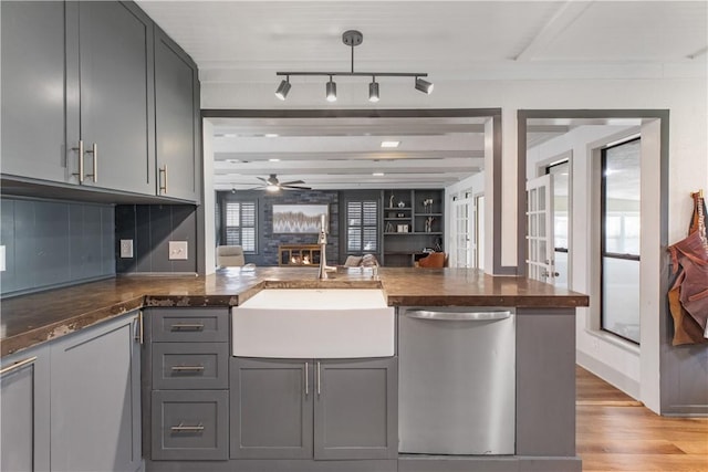 kitchen featuring gray cabinetry, light wood-style flooring, a sink, open floor plan, and dishwasher