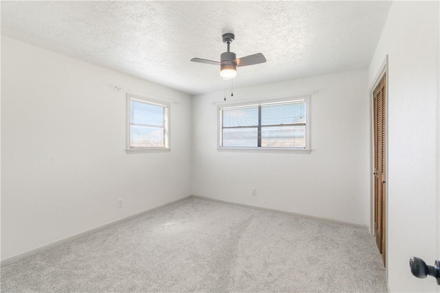 empty room featuring light carpet, baseboards, a textured ceiling, and ceiling fan