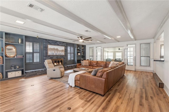 living room with visible vents, beam ceiling, a textured ceiling, and wood finished floors