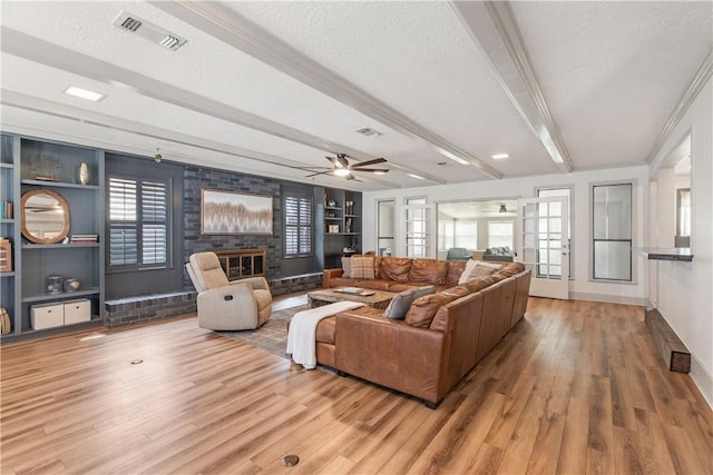 living area featuring beam ceiling, wood finished floors, visible vents, and a textured ceiling
