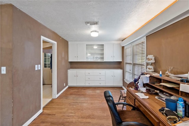 office with a textured ceiling and light wood-type flooring