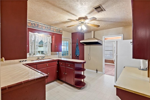 kitchen featuring sink, a textured ceiling, tile counters, kitchen peninsula, and extractor fan