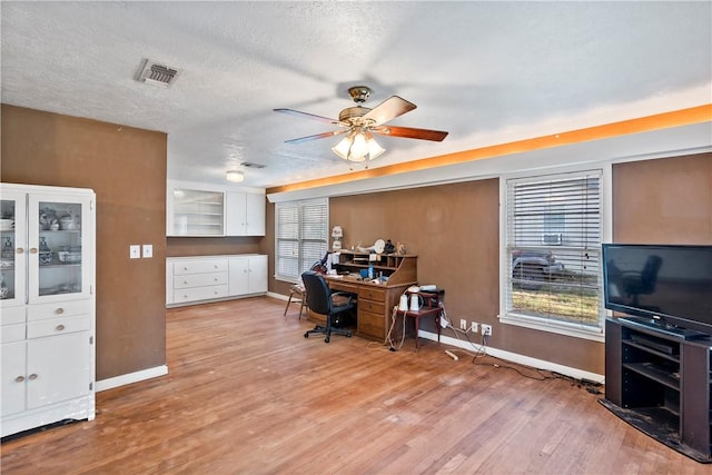 home office with a textured ceiling, light wood-type flooring, ceiling fan, and a healthy amount of sunlight