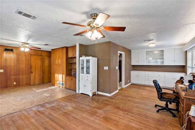 unfurnished office featuring ceiling fan, light wood-type flooring, and a textured ceiling