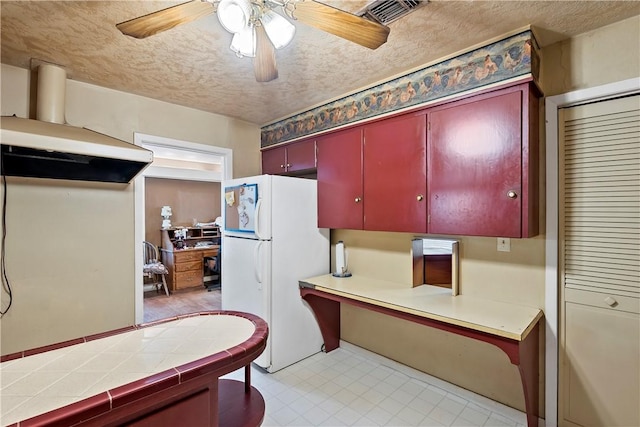 kitchen featuring a textured ceiling, white fridge, tile counters, and ceiling fan