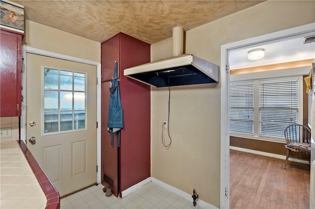 doorway to outside featuring light wood-type flooring and a textured ceiling