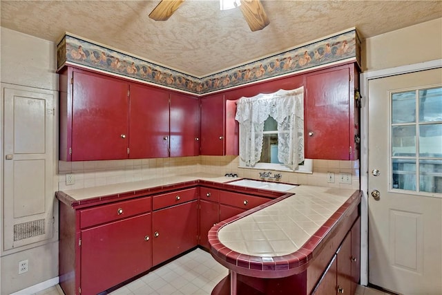 kitchen with backsplash, ceiling fan, tile counters, and sink