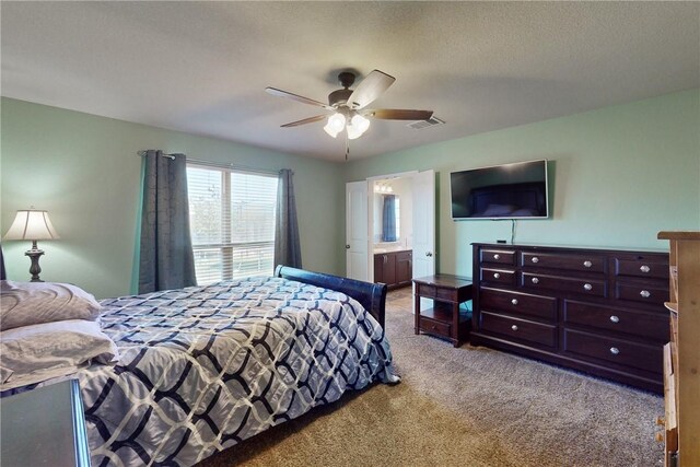 bedroom featuring a textured ceiling, light colored carpet, ensuite bath, and ceiling fan