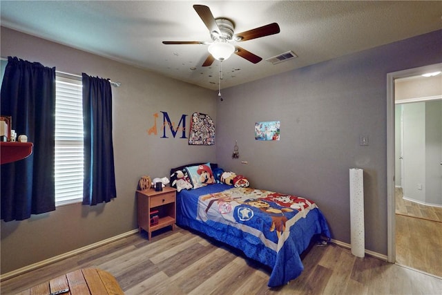 bedroom with hardwood / wood-style flooring, ceiling fan, and multiple windows