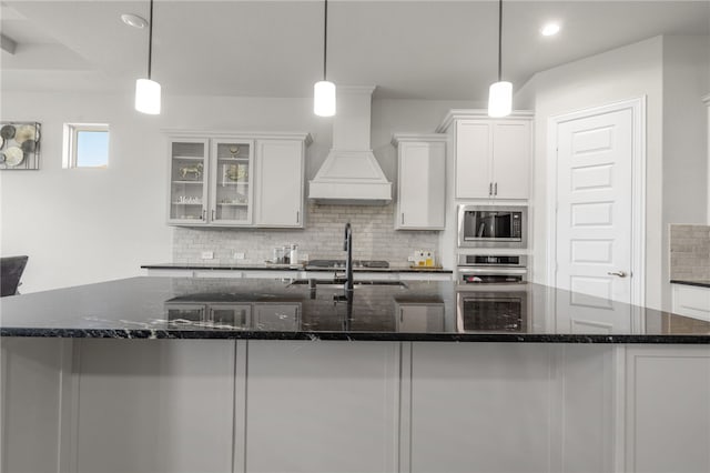 kitchen featuring appliances with stainless steel finishes, hanging light fixtures, and custom range hood