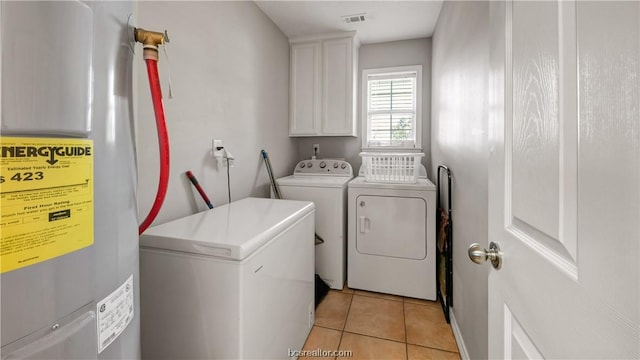 laundry area featuring separate washer and dryer, electric water heater, light tile patterned floors, and cabinets