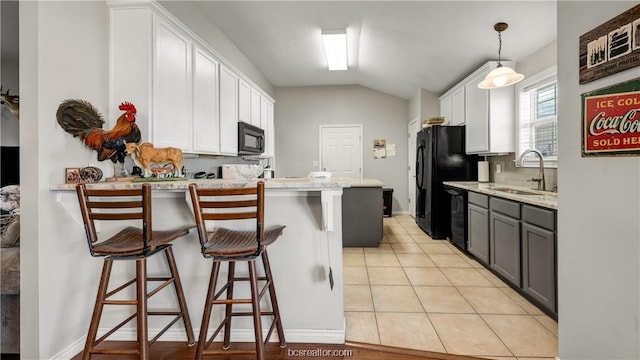 kitchen featuring gray cabinetry, white cabinets, a kitchen breakfast bar, black appliances, and sink