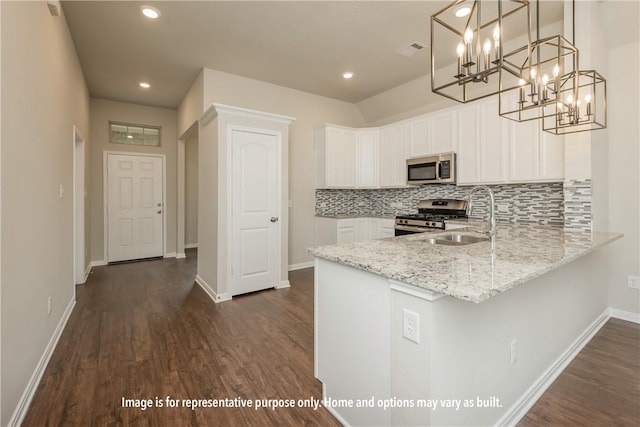 kitchen featuring light stone counters, stainless steel appliances, a sink, visible vents, and backsplash