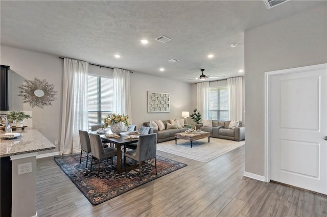 dining space with a textured ceiling, hardwood / wood-style flooring, and ceiling fan