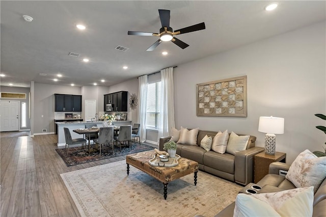 living room with ceiling fan and light hardwood / wood-style flooring