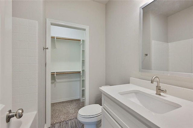 bathroom featuring toilet, vanity, a shower, a walk in closet, and a bathtub