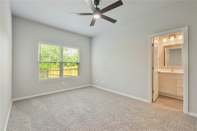 unfurnished bedroom with baseboards, ensuite bath, ceiling fan, carpet, and a sink