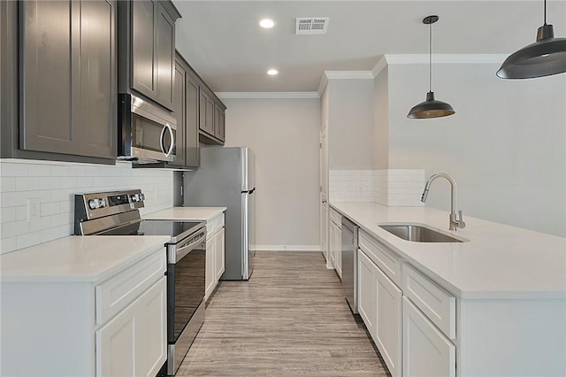 kitchen featuring visible vents, appliances with stainless steel finishes, ornamental molding, a peninsula, and a sink