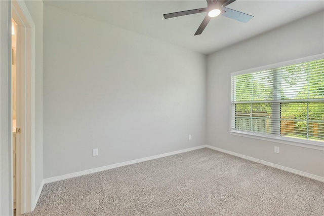 carpeted spare room featuring baseboards and a ceiling fan