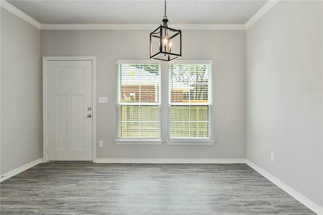 unfurnished dining area featuring baseboards, crown molding, a chandelier, and wood finished floors