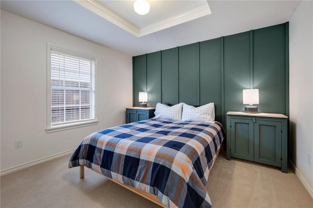 bedroom featuring baseboards, light colored carpet, ornamental molding, a decorative wall, and a raised ceiling