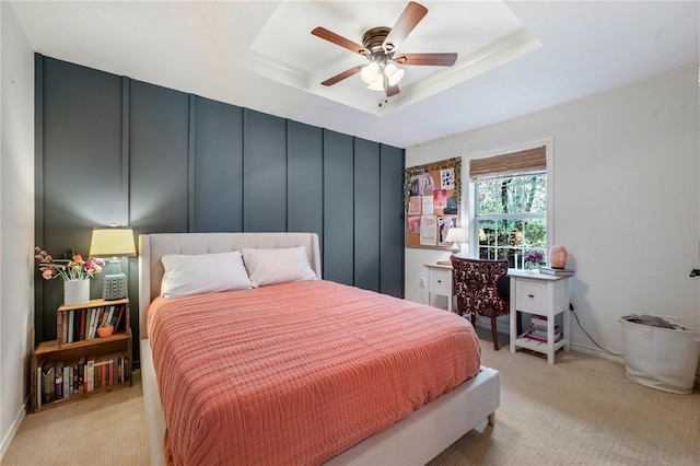 bedroom with light carpet, a decorative wall, a raised ceiling, and ceiling fan