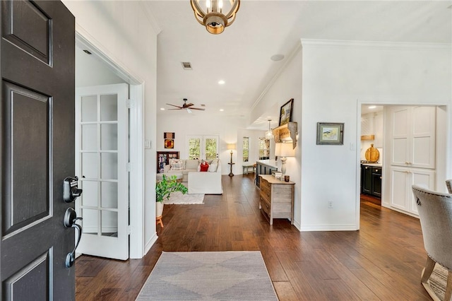 entryway featuring visible vents, ceiling fan with notable chandelier, dark wood-style floors, crown molding, and baseboards