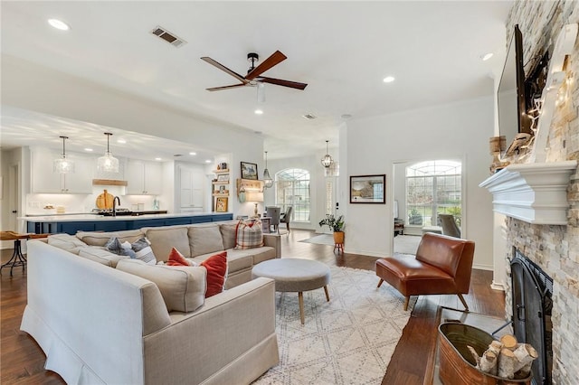 living area with recessed lighting, visible vents, light wood-style floors, and a stone fireplace