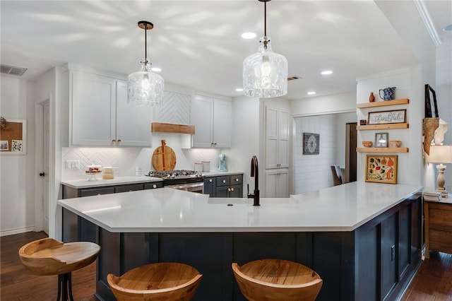 kitchen with stainless steel gas range oven, visible vents, a kitchen bar, a sink, and light countertops