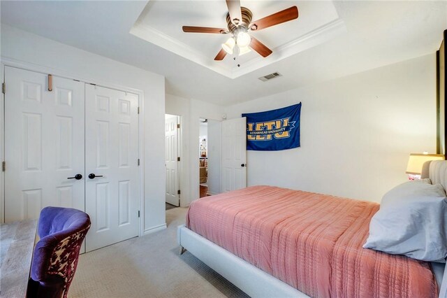 bedroom with visible vents, carpet floors, a closet, a raised ceiling, and a ceiling fan