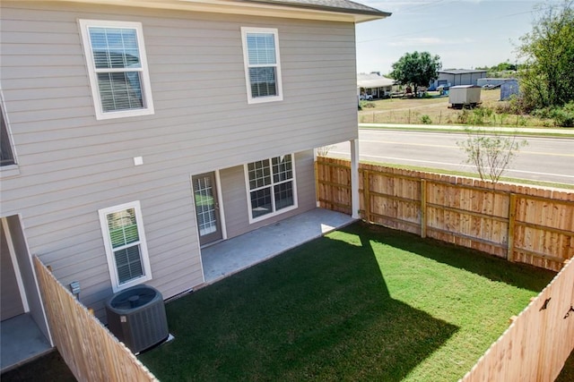 back of property with a patio area, a fenced backyard, central AC unit, and a lawn