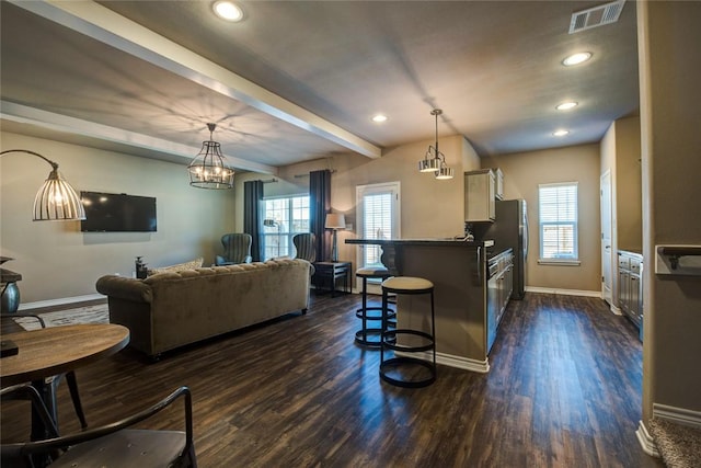 kitchen featuring a breakfast bar, pendant lighting, dark countertops, visible vents, and open floor plan