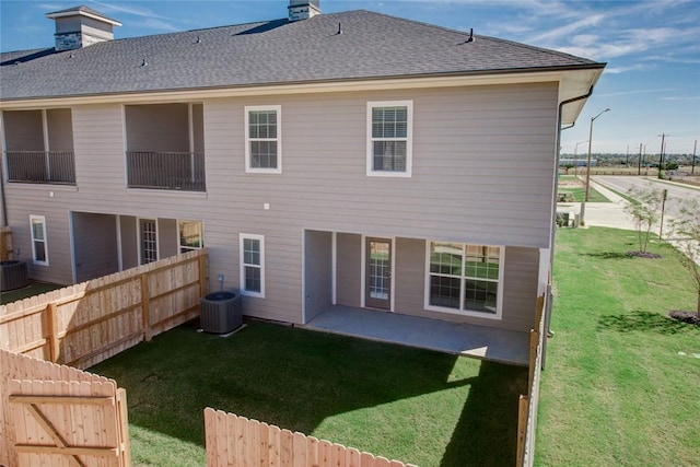 back of house featuring a patio area, a chimney, fence, and roof with shingles