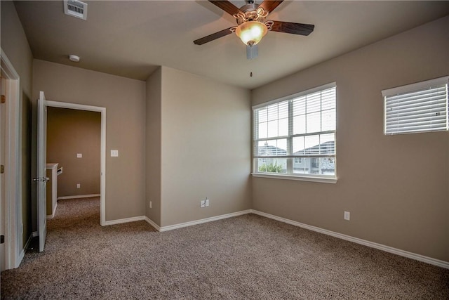 carpeted empty room with ceiling fan, visible vents, and baseboards