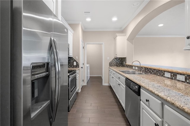 1403 Crescent Ridge Dr, College Station, TX 77845 - kitchen with appliances with stainless steel finishes, arched walkways, white cabinetry, tasteful backsplash, and ornamental molding