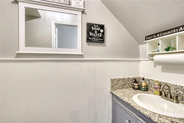 1681 Union Rd, Madisonville, TX 77864 - bathroom featuring vaulted ceiling, a textured ceiling, vanity, and decorative backsplash