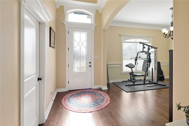 entryway with a healthy amount of sunlight, hardwood / wood-style flooring, baseboards, and crown molding