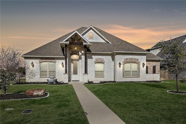 french provincial home featuring a shingled roof, a yard, and fence