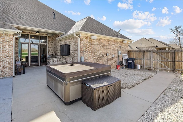 view of patio featuring a gate, fence, and a hot tub