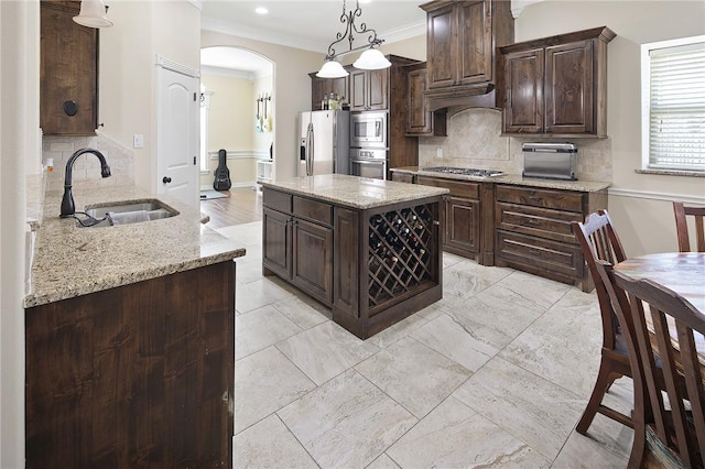 kitchen with arched walkways, light stone counters, stainless steel appliances, a sink, and dark brown cabinets