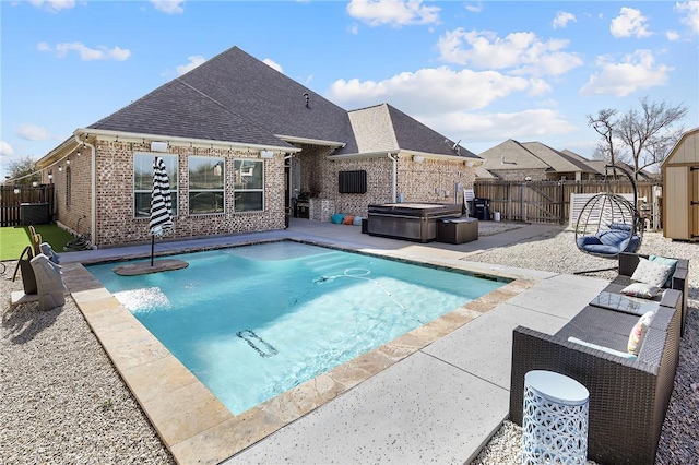 view of swimming pool featuring a hot tub, an outbuilding, a fenced backyard, and a patio