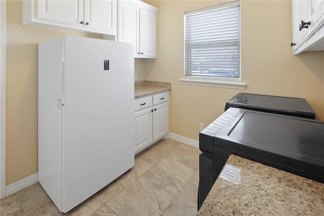 laundry room featuring cabinet space and baseboards