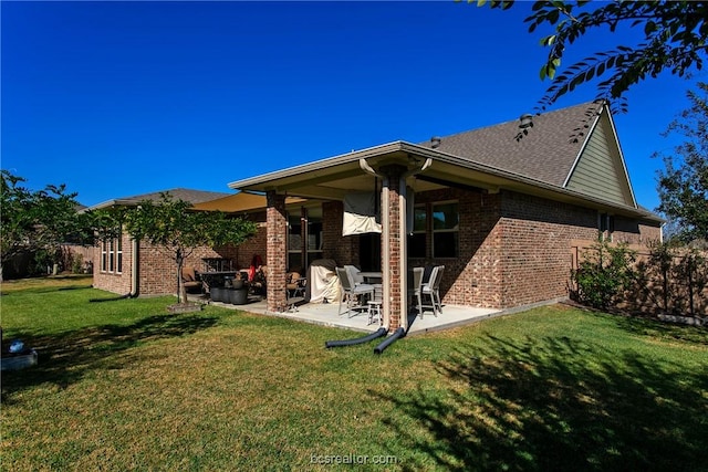 back of property featuring a patio, a yard, and brick siding